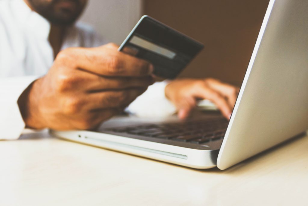 man holding a credit card making a payment on a computer